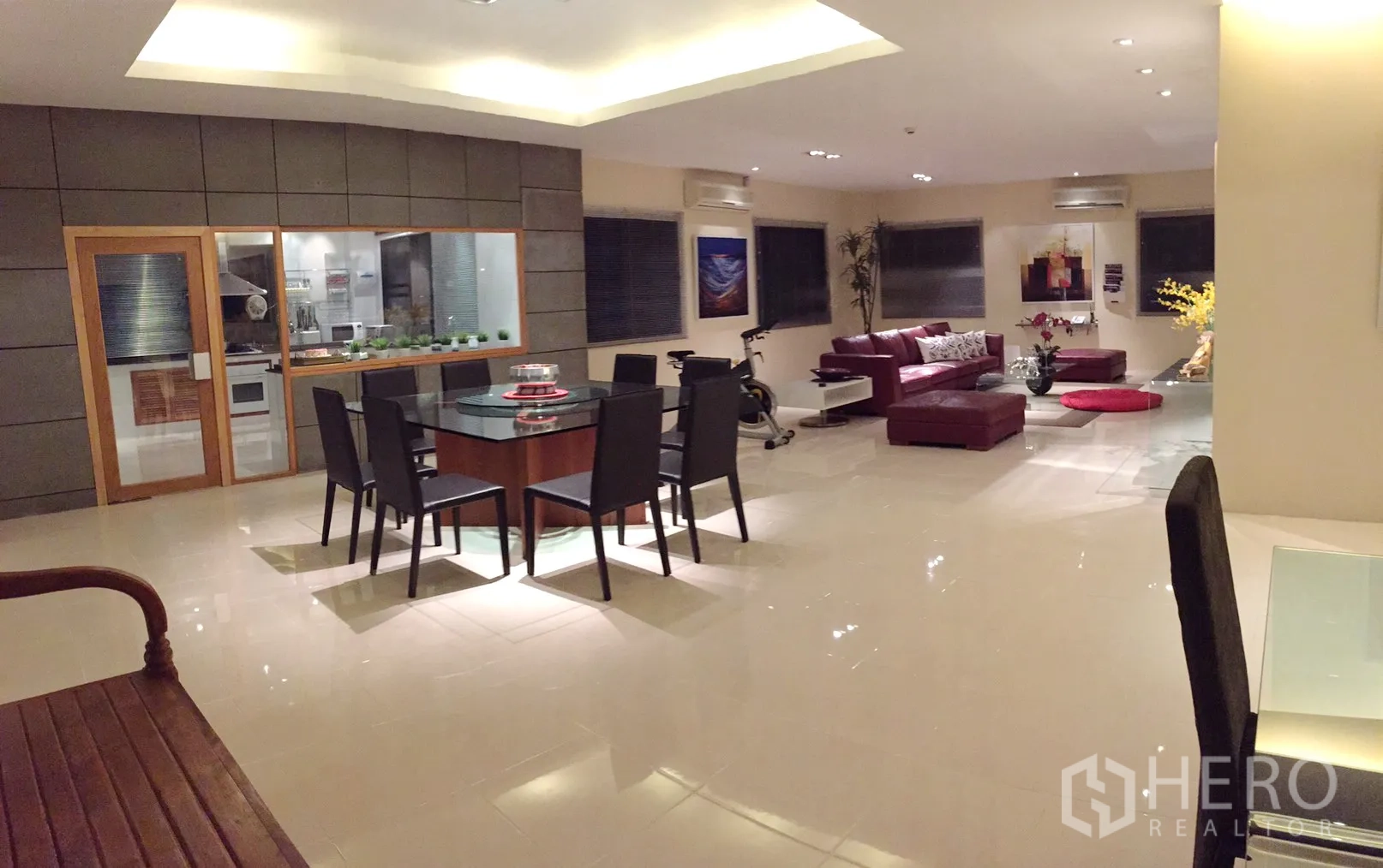 公寓 出租在Bang Rak, Bangkok - 开放式客餐厅，玻璃隔断厨房与红色皮沙发，地面光亮。