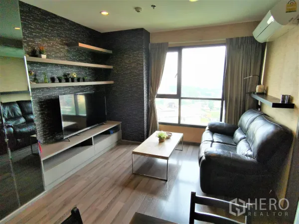 公寓 出租或出售在Watthana, Bangkok - 客厅配黑色皮沙发、电视柜、置物层板及大幅观景窗。