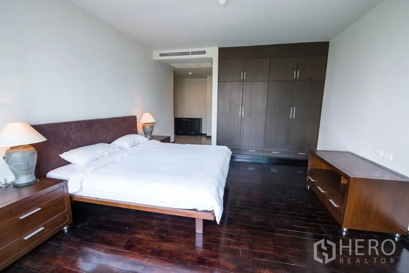 Condominium for rent in Sathon, Bangkok - Large bedroom with wood floors, bedside tables and built-in wardrobes.