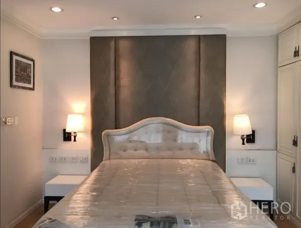 公寓 出租或出售在Sathon, Bangkok - 主卧配软包床头、墙壁壁灯与温暖中性色调。