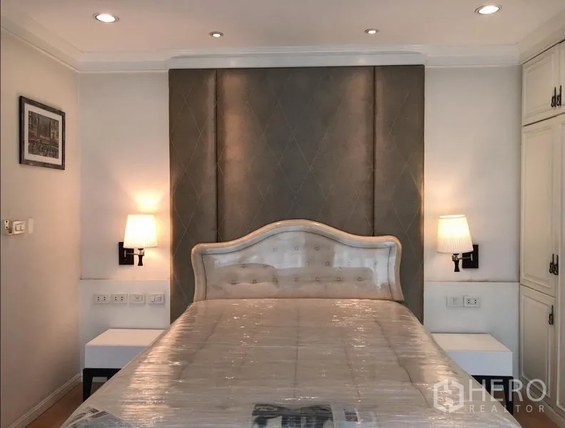 公寓 出租或出售在Sathon, Bangkok - 主卧配软包床头、墙壁壁灯与温暖中性色调。