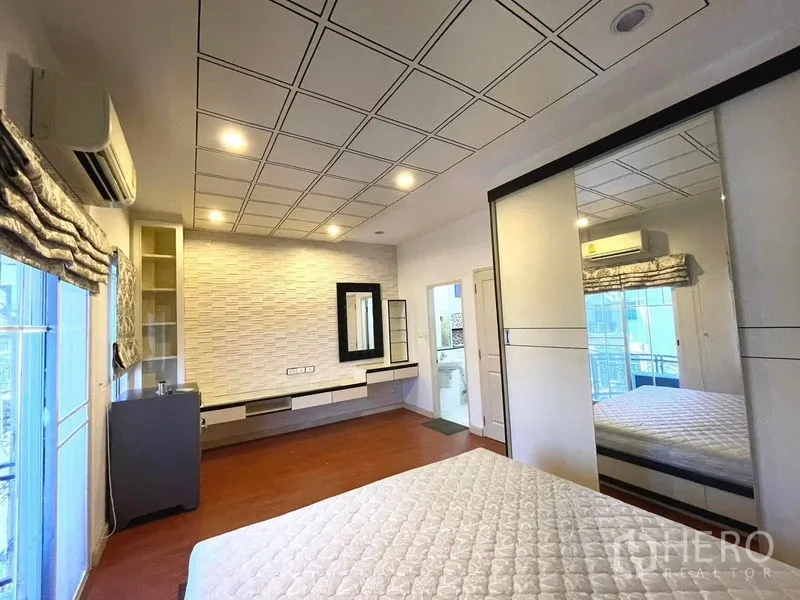 Townhouse for rent in Saphan Sung, Bangkok - Master bedroom from another angle showing built‑in wardrobe, vanity and ensuite entrance.