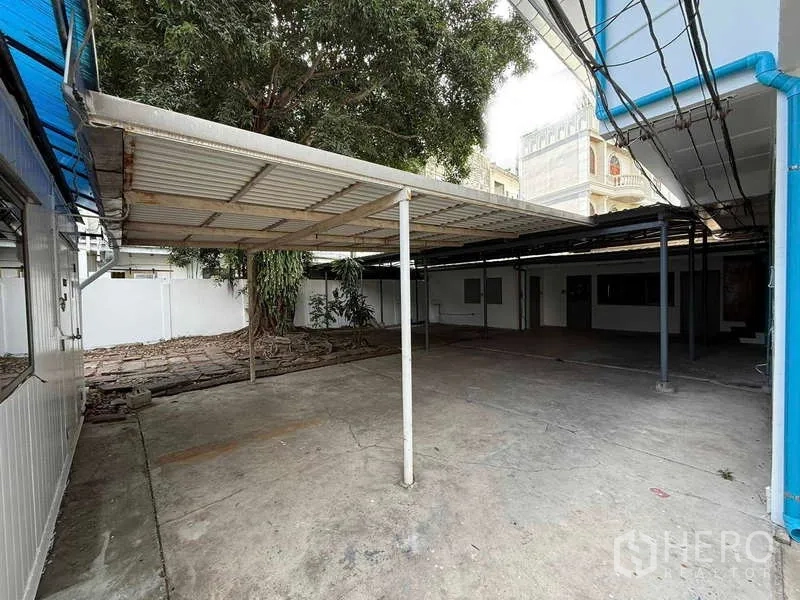 独立式住宅 出租在Watthana, Bangkok - 带金属顶棚的有顶车棚，紧邻房屋的硬化地面。