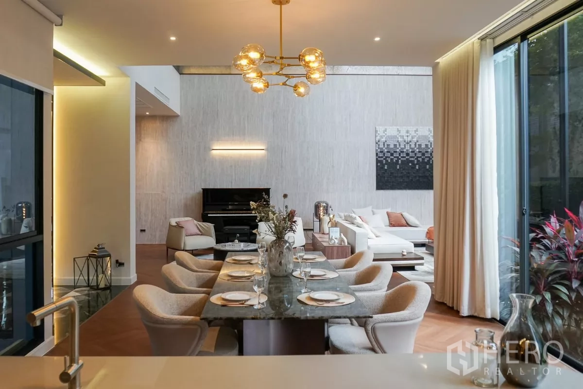 独立式住宅 出租或出售在Bang Kapi, Bangkok - 雅致餐厅，大理石餐桌与金色吊灯，后方为客厅与立式钢琴。