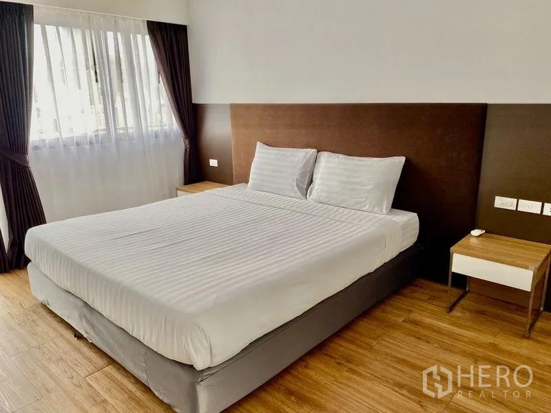 คอนโด ให้เช่าในKhlong Toei, Bangkok - ห้องนอนแขก เตียงใหญ่ หัวเตียงบุสีน้ำตาล และโต๊ะข้าง