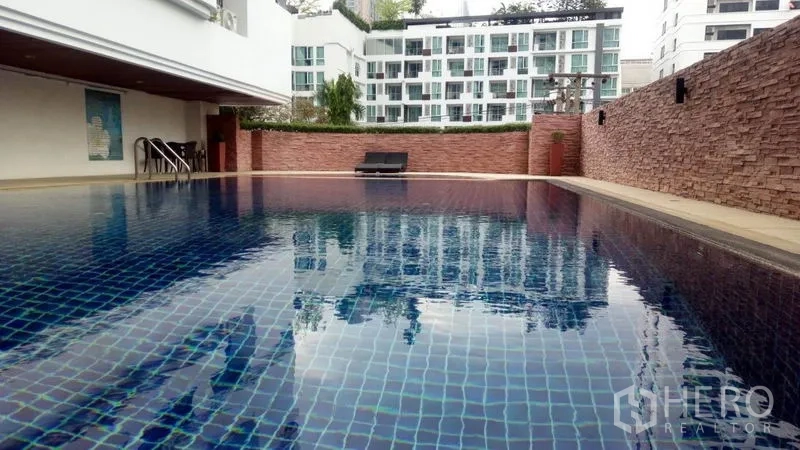 Condominium for rent in Watthana, Bangkok - Outdoor swimming pool with blue tiles and sun loungers.