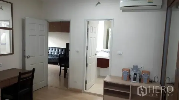 公寓 出租在Bang Rak, Bangkok - 室内一角，通往客厅与浴室的门，壁挂空调、书桌与置物架。