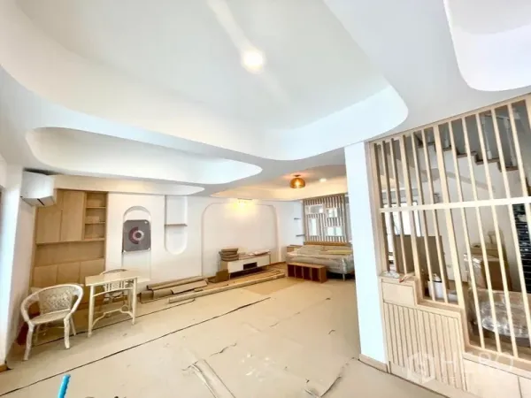 联排别墅 出租在Khlong Toei, Bangkok - 明亮客厅，弧形吊顶、木质格栅隔断与内置柜。