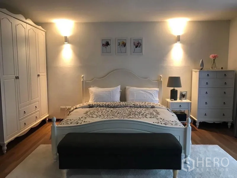 Townhouse for sale in Suan Luang, Bangkok - Elegant master suite with white bed frame, wardrobes and accent wall lights.