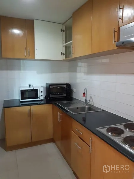 คอนโด ขายในWatthana, Bangkok - ห้องครัวบิวท์อินตู้ไม้ ท็อปสีดำ อ่างล้างจานคู่ เตาไฟฟ้า ไมโครเวฟ และเตาอบ