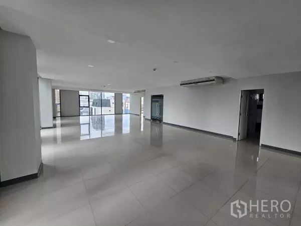Office Space for rent in Sathon, Bangkok - Spacious open office with tiled floors, glass entry door, AC units and urban views.