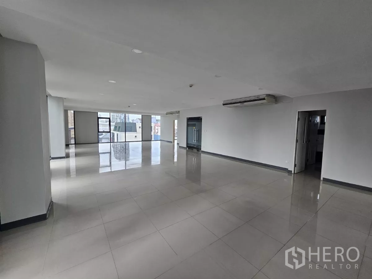 Office Space for rent in Sathon, Bangkok - Spacious open office with tiled floors, glass entry door, AC units and urban views.
