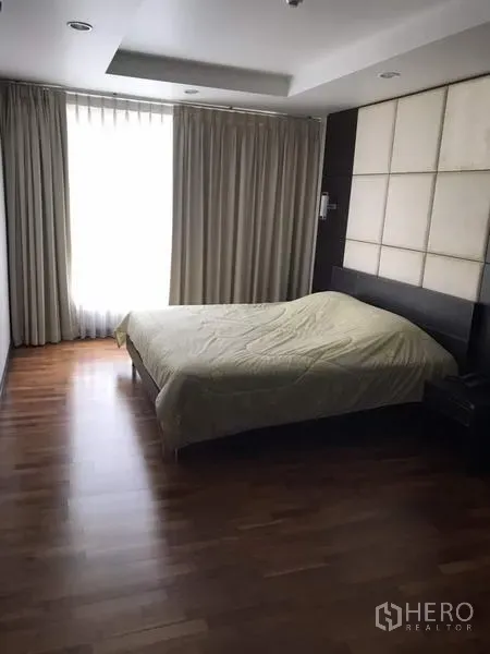 Condominium for rent in Watthana, Bangkok - Second bedroom with wood floors, feature headboard wall, wide window and drapes for natural light control.