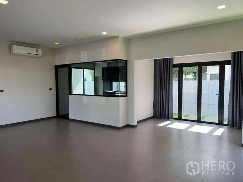 Detached House for rent or sale in Bang Phli, Samut Prakan - Open‑plan living room with kitchen pass‑through window and folding doors to the yard.