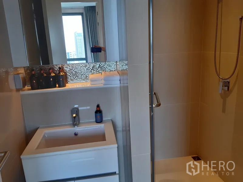 Condominium for rent in Watthana, Bangkok - Modern bathroom featuring a glass-enclosed shower and sleek white vanity.