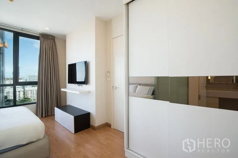 公寓 出租在Watthana, Bangkok - 卧室含大型推拉衣柜、木地板、壁挂电视与套内浴室门。