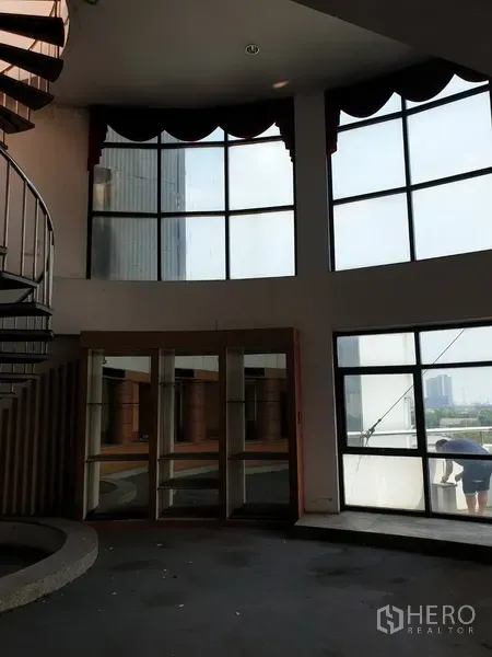 Office Space for rent in Suan Luang, Bangkok - Double-height office area with curved floor-to-ceiling windows and city views.