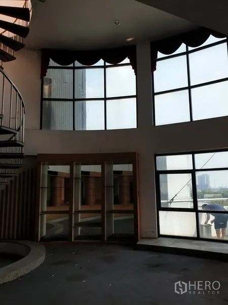 Office Space for rent in Suan Luang, Bangkok - Double-height office area with curved floor-to-ceiling windows and city views.