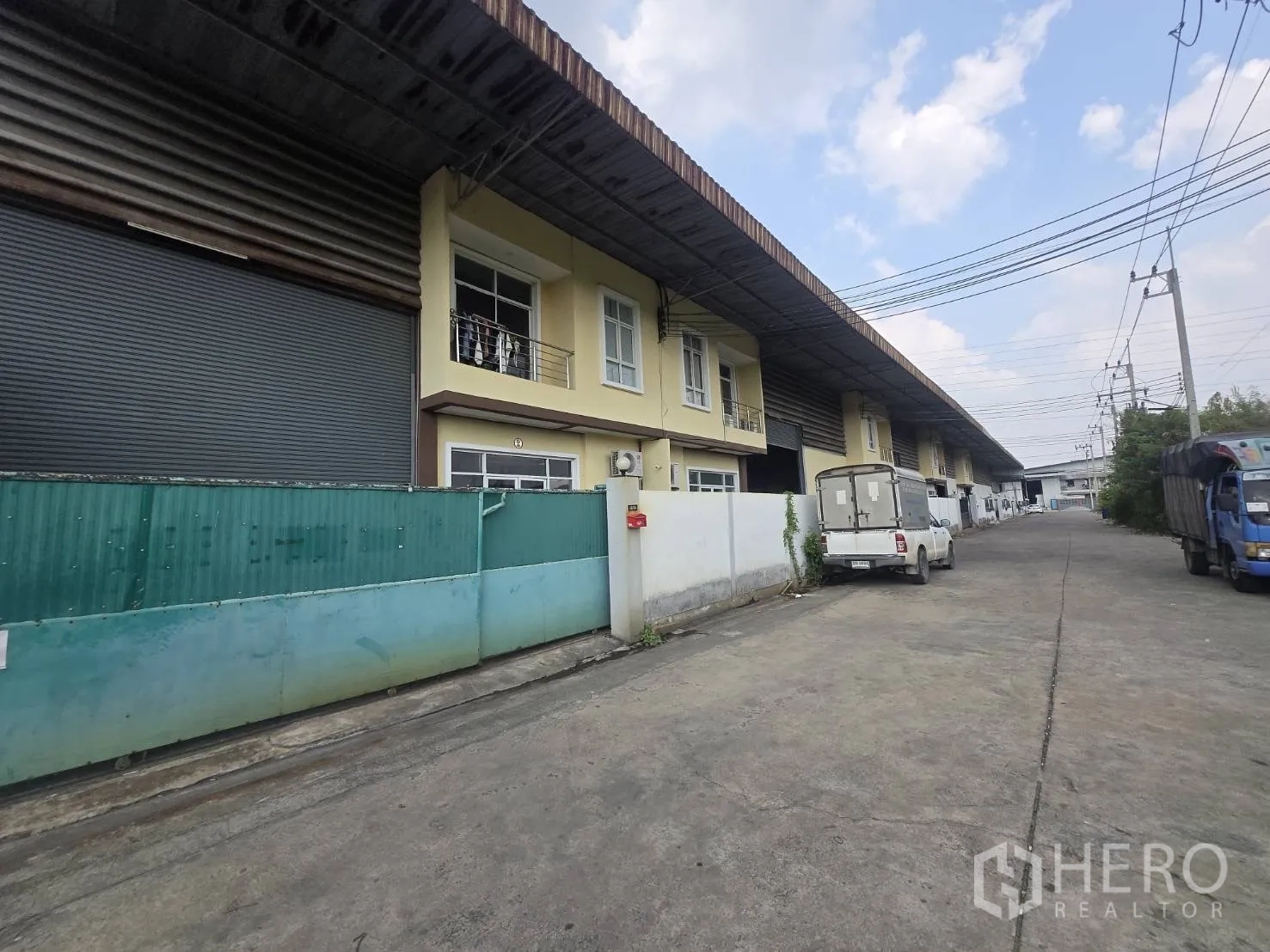 工厂 for rent or sale in Mueang Samut Sakhon, Samut Sakhon - 一排工厂沿宽阔混凝土道路布局，装卸与停车方便。