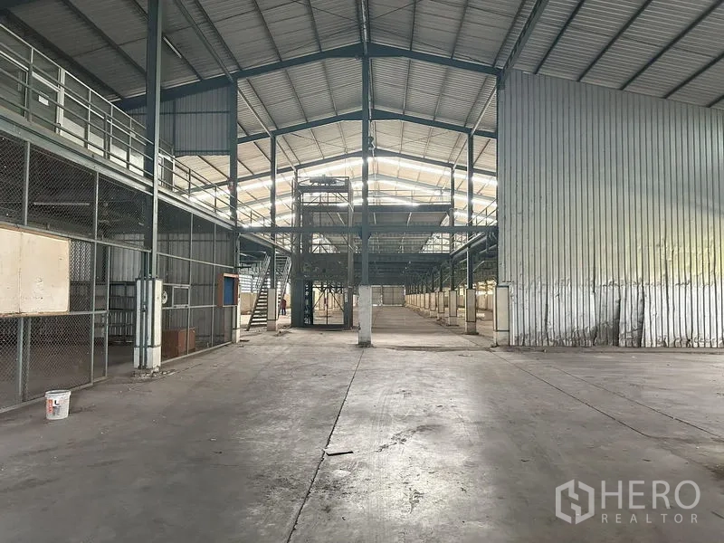 Factory for rent in Pathum Thani - Wide view of the factory showing mezzanine platforms, stairs and metal cladding.