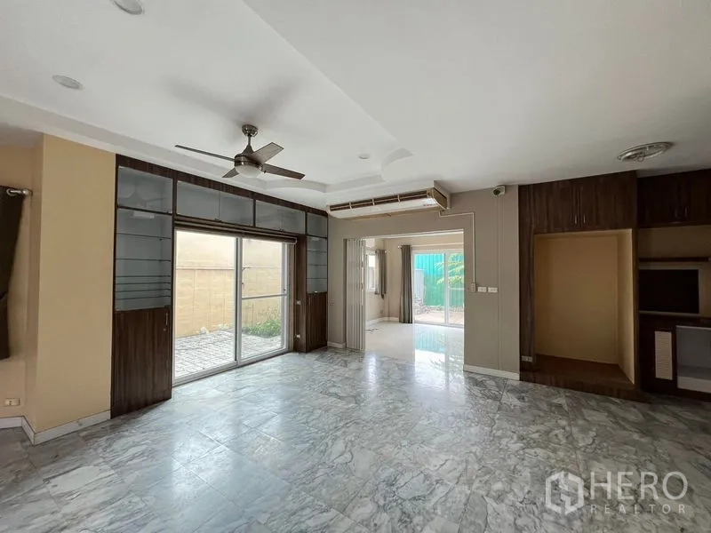 บ้าน ให้เช่าหรือขายในLak Si, Bangkok - ห้องนั่งเล่น พื้นหินอ่อน พัดลมเพดาน และประตูบานเลื่อนออกสู่ลาน