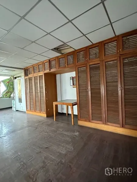 Shophouse for rent in Sathon, Bangkok - Upper-floor room featuring a long wall of wooden louvered built-in cabinets and a small desk.