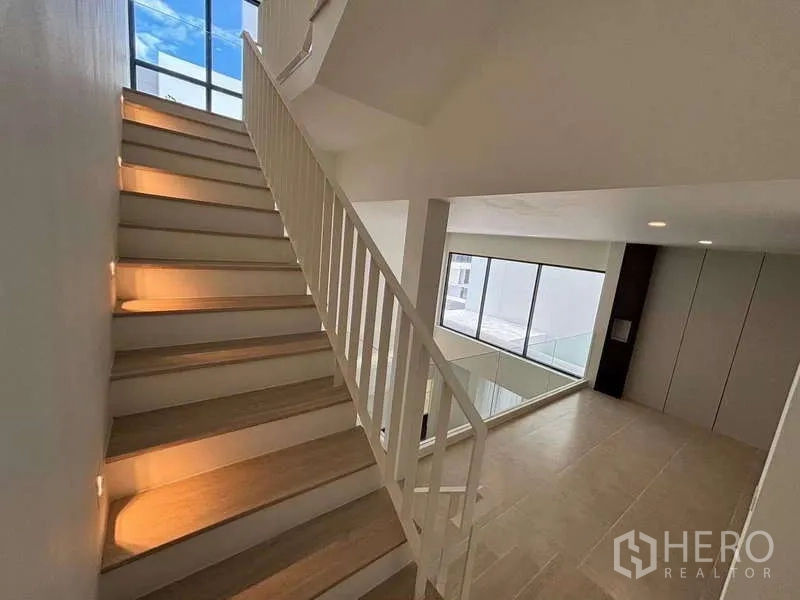 Townhouse for rent or sale in Don Mueang, Bangkok - Staircase with wood treads and a large window bringing in natural light.