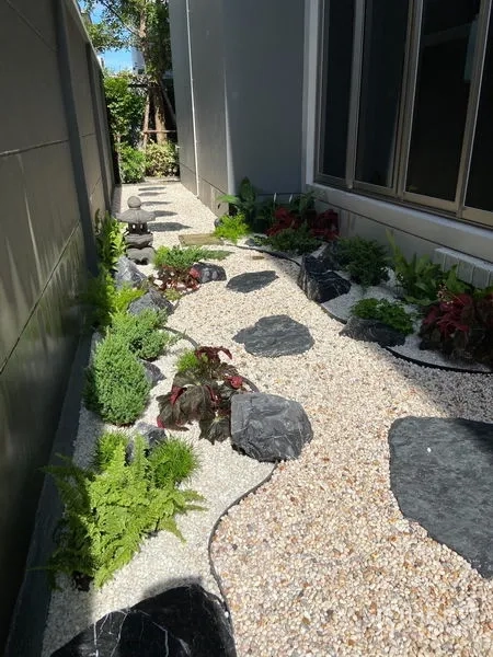 Detached House for sale in Bang Kapi, Bangkok - Side-yard rock garden with pebbles, stepping stones and lush plants along the home.