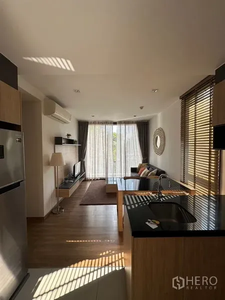 คอนโด ให้เช่าในWatthana, Bangkok - ห้องนั่งเล่นแบบเปิดเชื่อมครัว เคาน์เตอร์สีดำ พื้นไม้ พร้อมม่านโปร่งและระเบียง