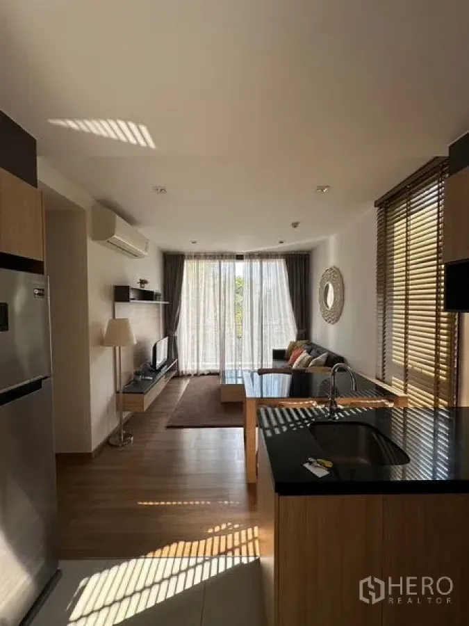 公寓 出租在Watthana, Bangkok - 开放式客厅与厨房岛台，木地板，大落地窗与纱帘通向阳台