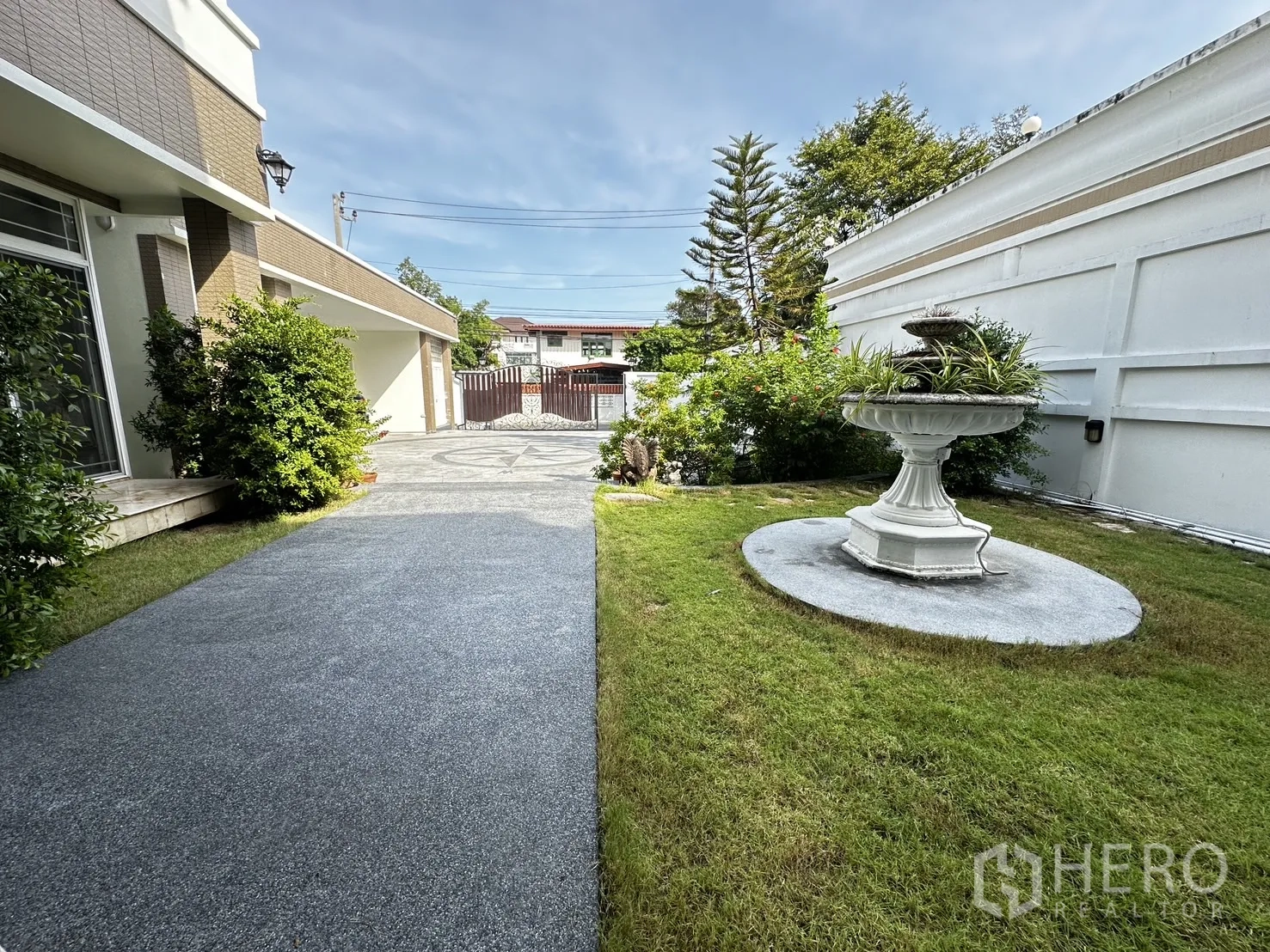 独立式住宅 出租在Chatuchak, Bangkok - 侧院草坪与白色喷泉，步道通向庭门