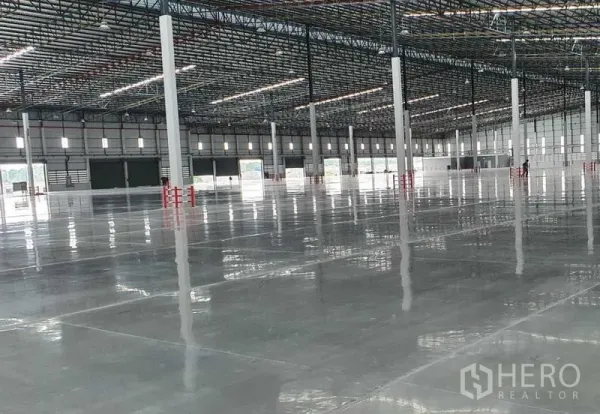 工厂 出租在Si Racha, Chon Buri - 仓库内部，沿墙多处装卸月台与卷帘门，宽阔柱网与光亮地面。