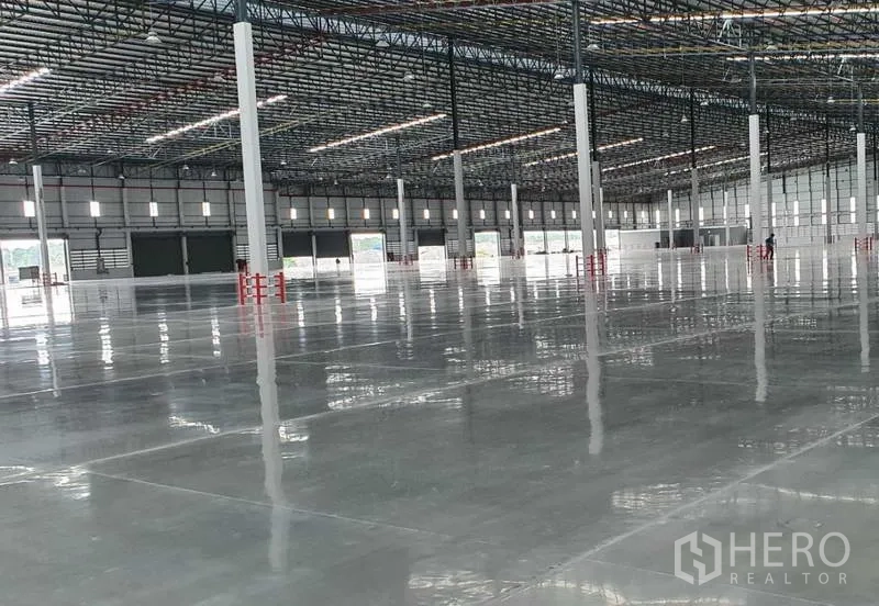 工厂 出租在Si Racha, Chon Buri - 仓库内部，沿墙多处装卸月台与卷帘门，宽阔柱网与光亮地面。