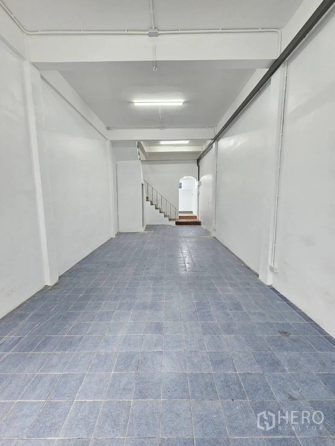 สำนักงานที่บ้าน ให้เช่าในKhlong Toei, Bangkok - พื้นที่โล่งชั้นล่าง ผนังสีขาว พื้นกระเบื้องสีน้ำเงิน และไฟเพดาน