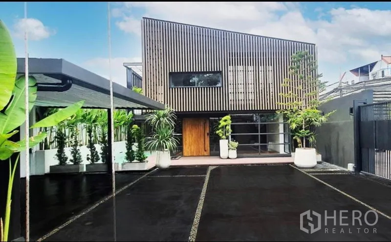 Home Office for rent or sale in Khlong Toei, Bangkok - Front driveway and parking court leading to a two-storey home office with wood-slat facade.