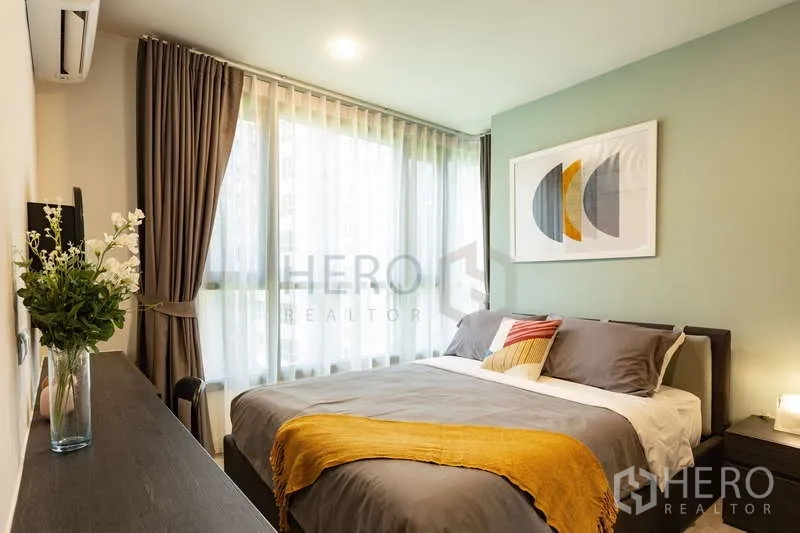 Condominium for rent or sale - Master bedroom with green accent wall, large windows and double bed.