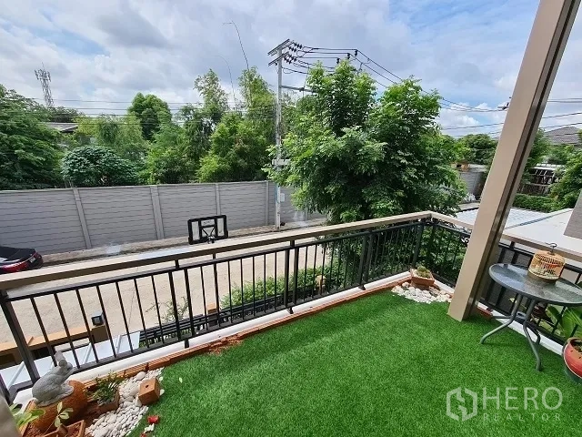 Detached House for sale in Suan Luang, Bangkok - Balcony with artificial grass overlooking a quiet street and mature trees.