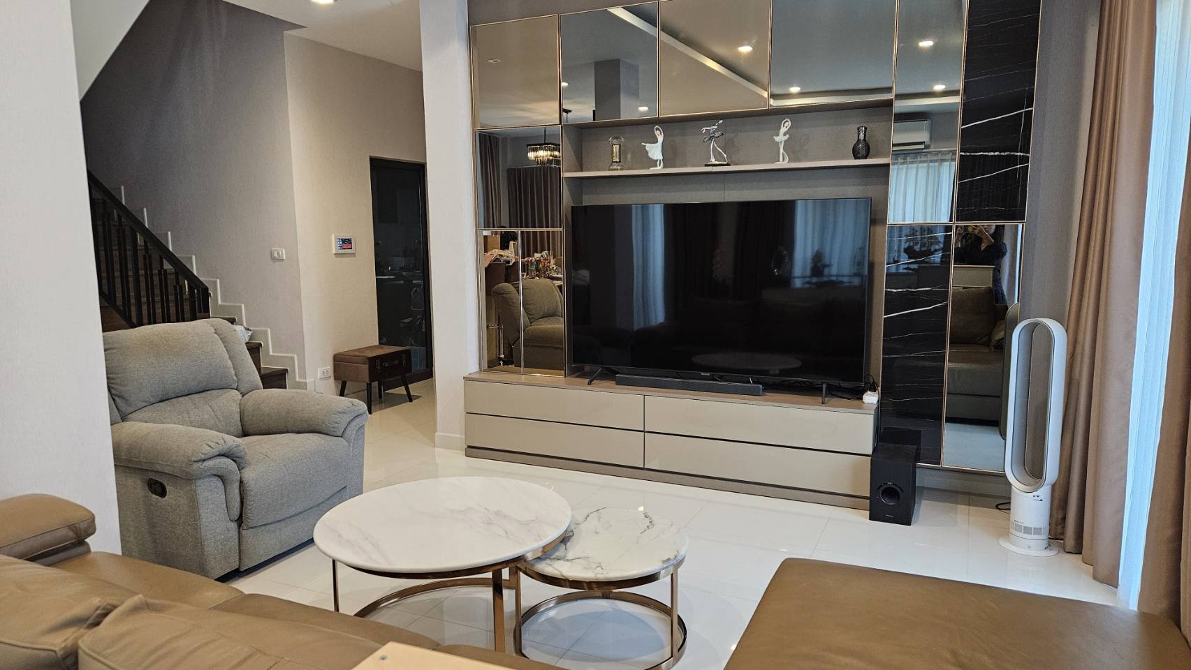 Detached House for rent in Saphan Sung, Bangkok - Entertainment wall with oversized TV, mirrored cabinetry and floor fan.