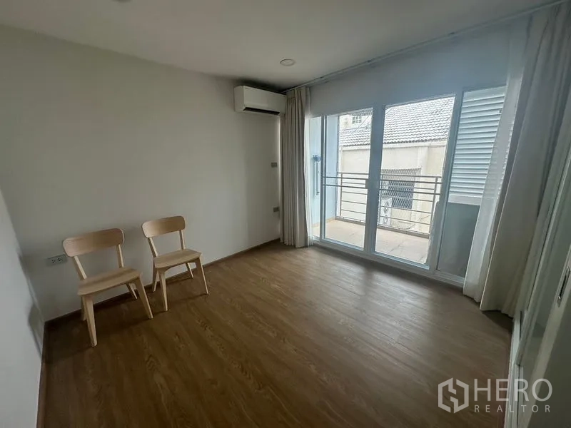Condominium for rent - Empty room with air conditioner, two chairs and floor-to-ceiling sliding doors to the balcony.
