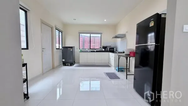 独立式住宅 出租或出售在Bang Phli, Samut Prakan - 宽敞厨房，白色橱柜与黑色台面，配抽油烟机、微波炉和大冰箱。