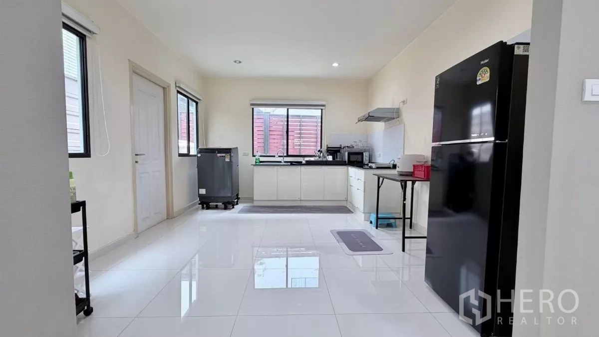 独立式住宅 出租或出售在Bang Phli, Samut Prakan - 宽敞厨房，白色橱柜与黑色台面，配抽油烟机、微波炉和大冰箱。