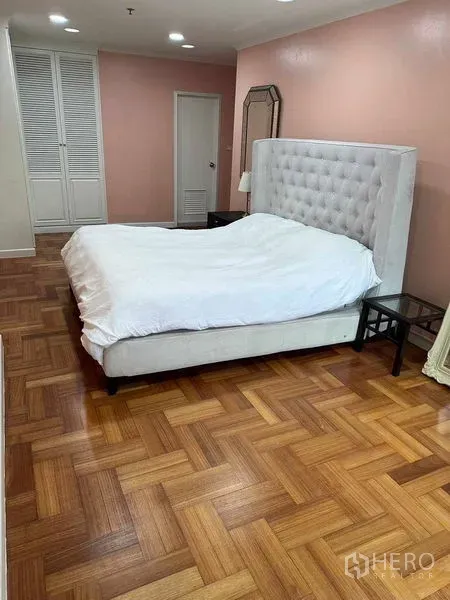 คอนโด ให้เช่าหรือขายในBangkok - ห้องนอนใหญ่ เตียงหัวเตียงบุผ้า ผนังสีชมพู และพื้นปาร์เกต์