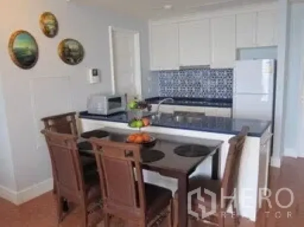 Condominium for rent in Khlong Toei, Bangkok - Compact kitchen with white cabinets, blue patterned backsplash, breakfast bar and dining chairs.