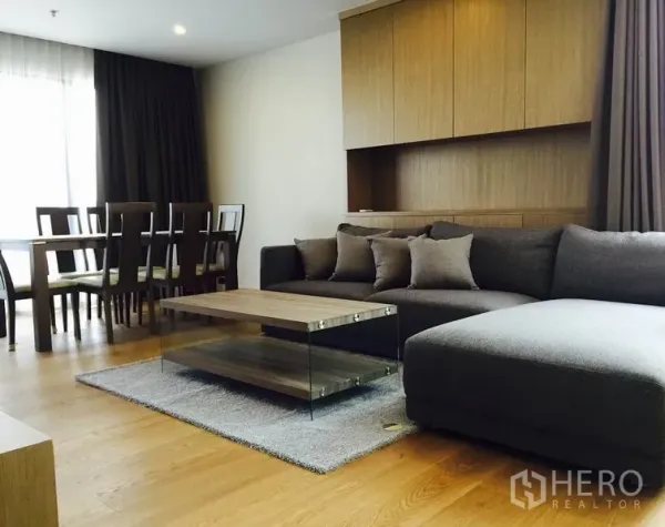 คอนโด ให้เช่าในWatthana, Bangkok - ห้องนั่งเล่นพร้อมโซฟาเข้ามุมสีเทา โต๊ะกลางกระจกกับไม้ ชุดโต๊ะทานอาหาร และตู้บิวท์อิน