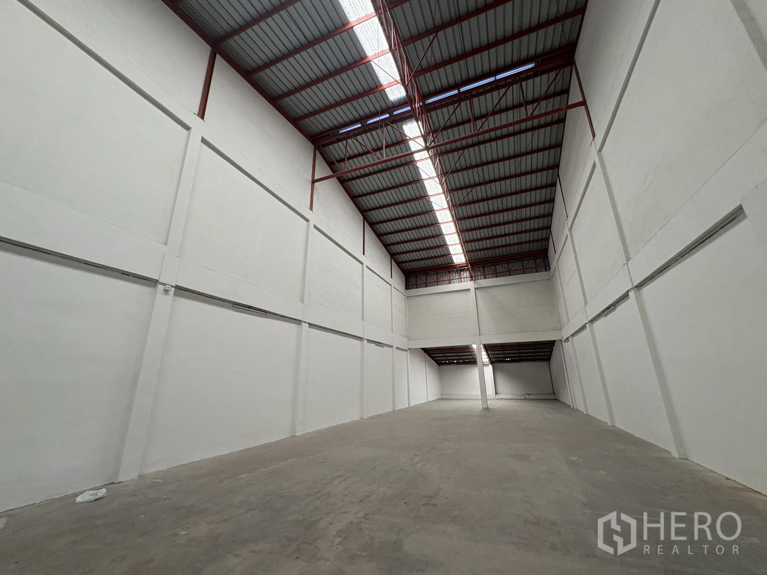 โรงงาน ให้เช่าในPhra Samut Chedi, Samut Prakan - มุมมองยาวของโกดัง แสดงหลังคาโปร่งแสงและผนังสีขาวสูง