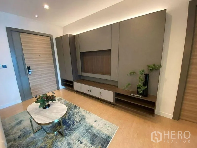 公寓 出售在Bang Rak, Bangkok - 入口客厅配有定制电视墙、低矮柜与地毯装饰。