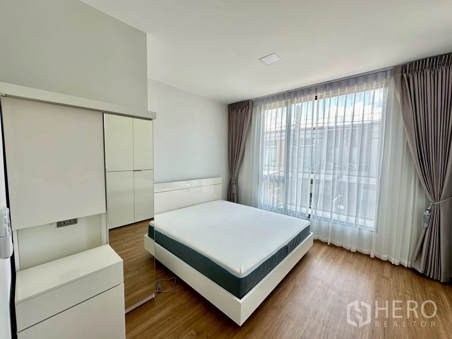 Townhouse for rent in Bang Phli, Samut Prakan - Sunny bedroom with double bed, wardrobe and full-height windows.