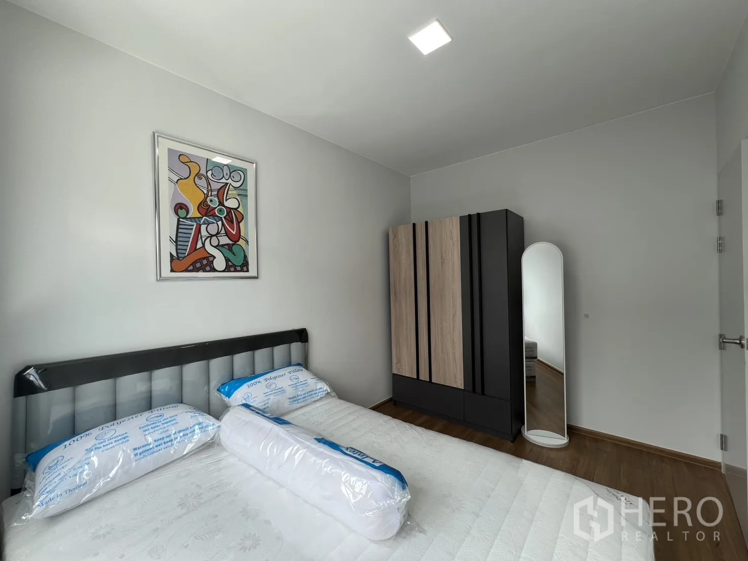 Townhouse for rent in Bang Phli, Samut Prakan - Cozy bedroom showing bed, wall art, and a closet beside a standing mirror.