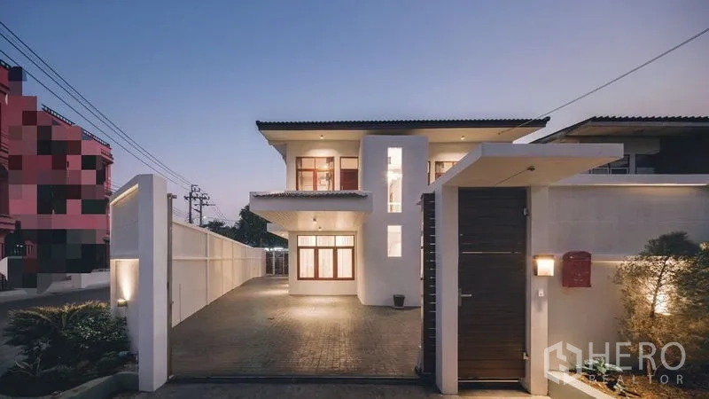 独立式住宅 出售在Chatuchak, Bangkok - 两层现代独栋住宅外观，傍晚灯光与电动大门车道。