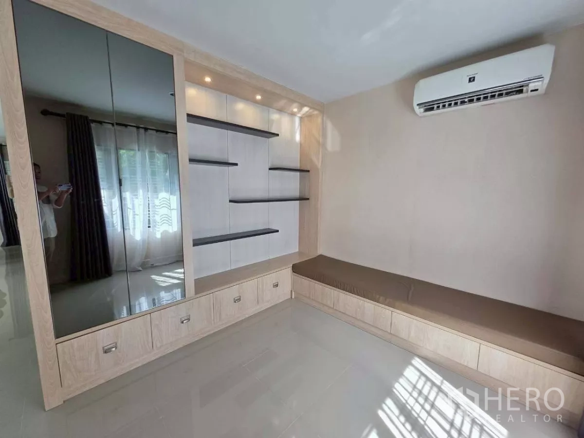 Detached House for rent or sale in Samut Prakan - Cozy lounge with wall shelves, mirrored cabinet and air-conditioning unit.